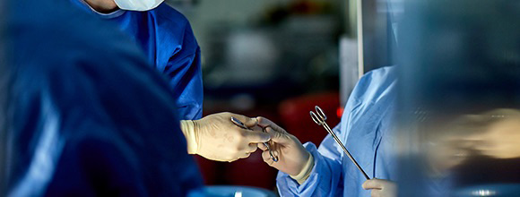 Staff handing surgery tools to the surgeon.